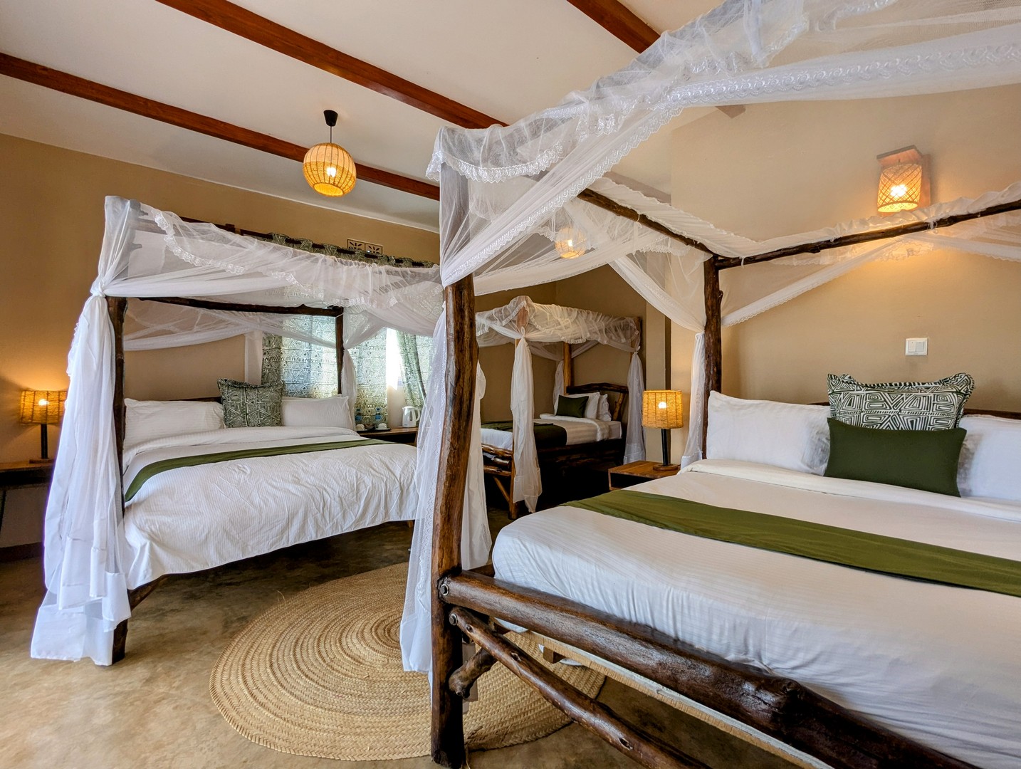 Twin four-poster beds with mosquito nets in a Mvuli Lodge family cottage