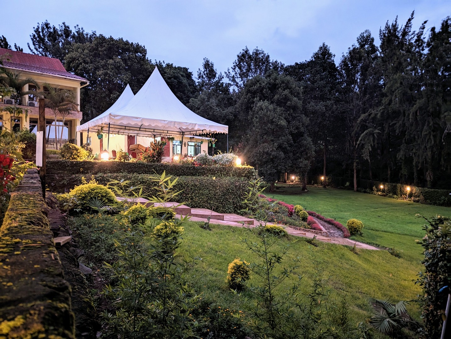 Peaked garden dining tent at Mvuli Lodge lit up at dusk