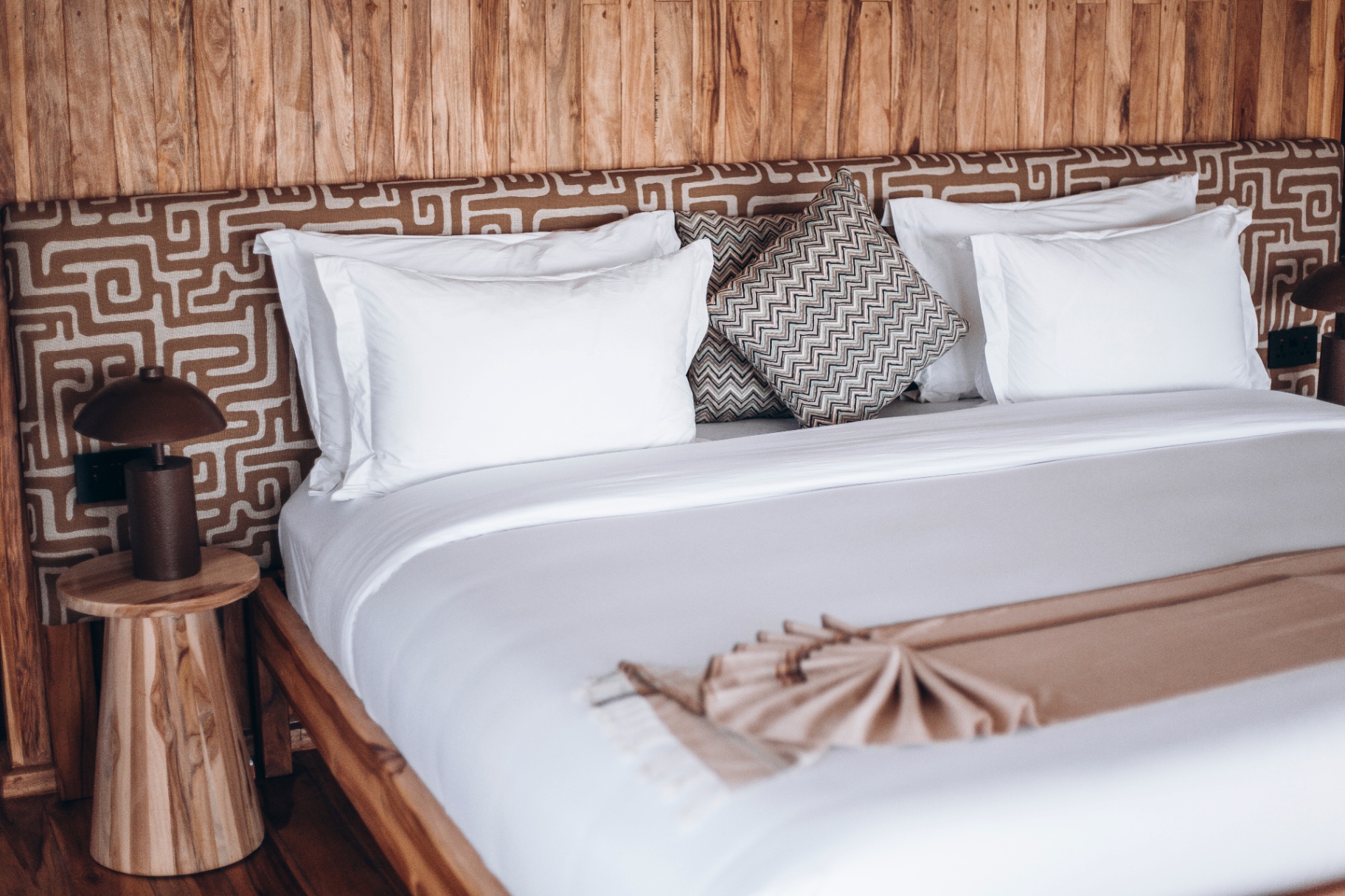 King bed with kuba-print headboard at Conserve Safari
